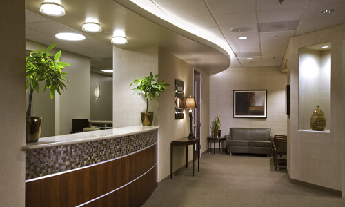 Picture of a dental center reception area in San Jose, Costa Rica.  The interior of the reception area is well lighted with light brown and cream colors.